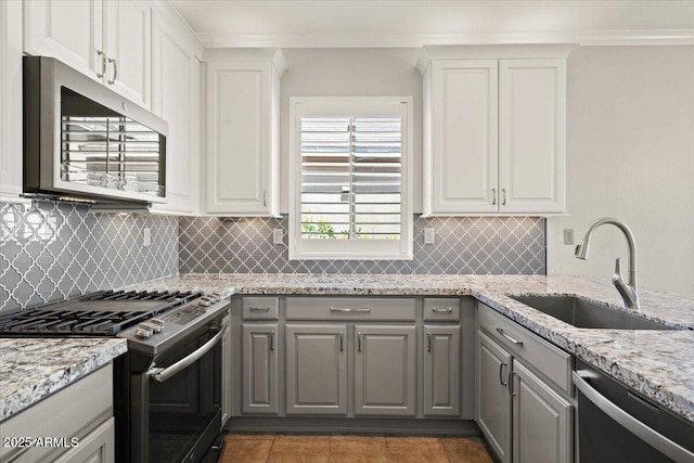 kitchen featuring stainless steel appliances, gray cabinetry, sink, white cabinets, and dark tile patterned floors