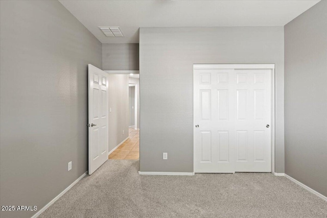 unfurnished bedroom with light colored carpet and a closet