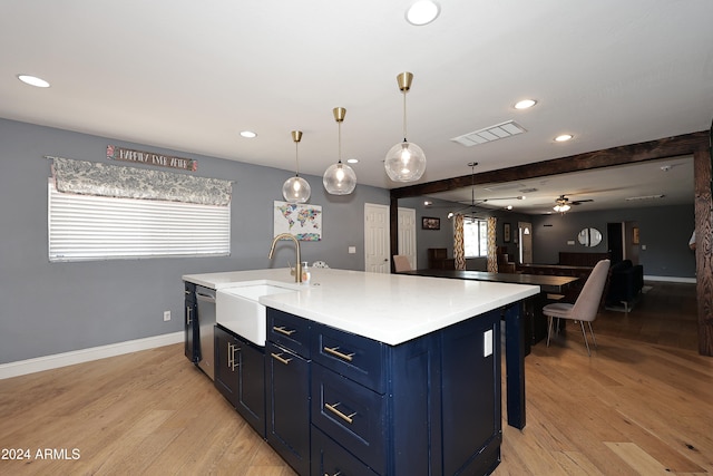 kitchen with pendant lighting, light wood-type flooring, blue cabinets, and an island with sink