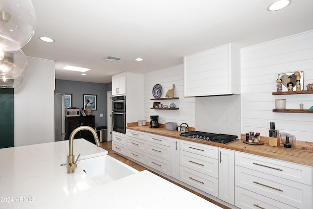 kitchen featuring butcher block countertops, sink, gas stovetop, and white cabinets