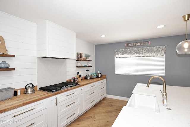 kitchen with butcher block countertops, white cabinetry, light hardwood / wood-style flooring, and decorative light fixtures