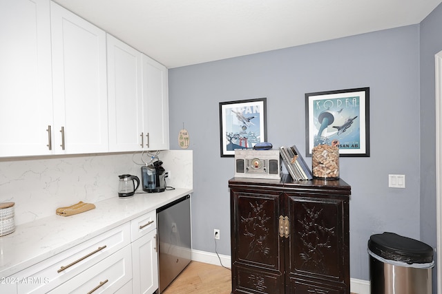 bar with white cabinetry, light stone counters, stainless steel fridge, light hardwood / wood-style floors, and decorative backsplash