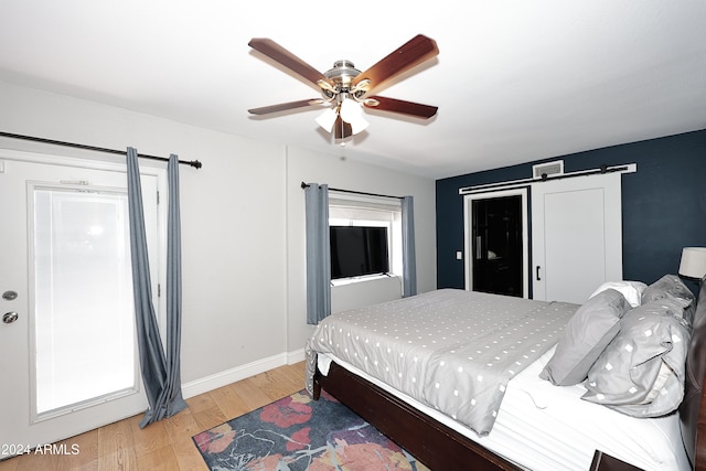 bedroom featuring wood-type flooring, a barn door, and ceiling fan