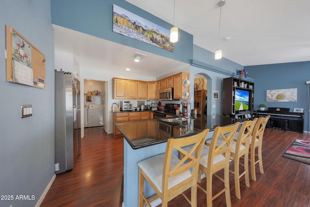 kitchen featuring appliances with stainless steel finishes, sink, a kitchen bar, kitchen peninsula, and washing machine and dryer