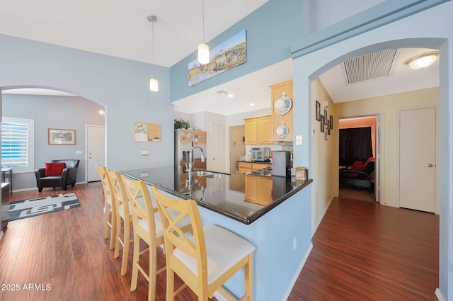 kitchen featuring sink, dark wood-type flooring, hanging light fixtures, kitchen peninsula, and light brown cabinets