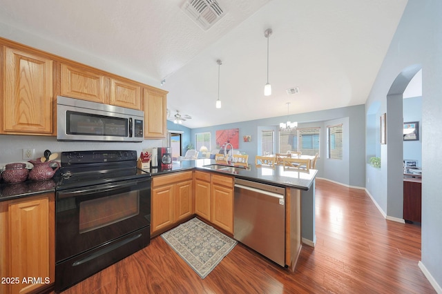 kitchen with sink, appliances with stainless steel finishes, a wealth of natural light, decorative light fixtures, and kitchen peninsula