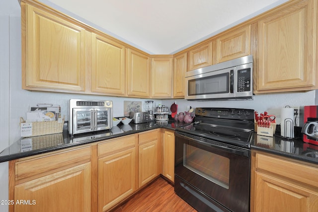 kitchen with dark stone countertops, black electric range oven, and light wood-type flooring