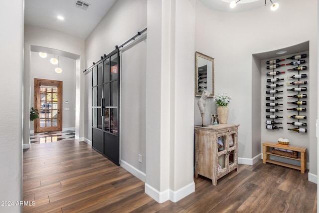 corridor with a barn door and dark hardwood / wood-style floors