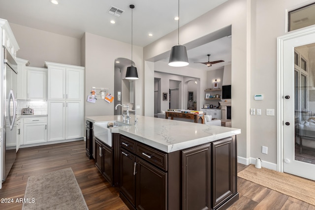 kitchen with ceiling fan, decorative light fixtures, light stone counters, and dark hardwood / wood-style flooring