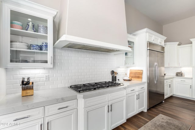 kitchen with decorative backsplash, white cabinets, premium range hood, dark wood-type flooring, and stainless steel appliances