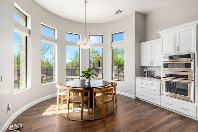 dining space featuring a wealth of natural light, dark wood-type flooring, a towering ceiling, and a chandelier