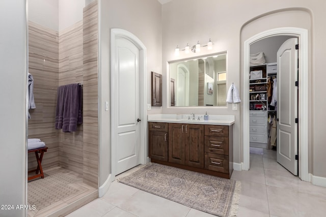 bathroom with vanity, a tile shower, and tile patterned flooring