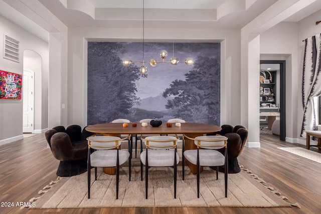 dining area with hardwood / wood-style flooring and a raised ceiling