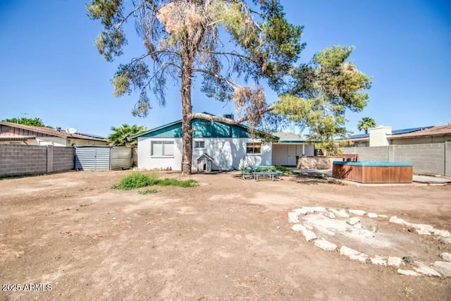 back of property featuring a fenced backyard and a hot tub