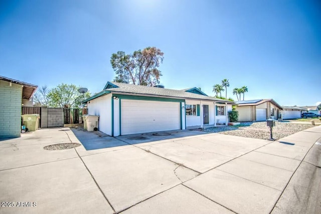 ranch-style house featuring an attached garage, driveway, and fence