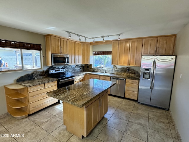 kitchen with a kitchen island, dark stone counters, light tile patterned flooring, stainless steel appliances, and a sink