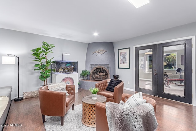 living room featuring a fireplace, wood finished floors, baseboards, and french doors