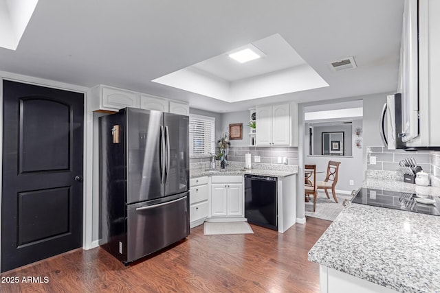 kitchen featuring visible vents, stainless steel appliances, white cabinetry, a raised ceiling, and tasteful backsplash