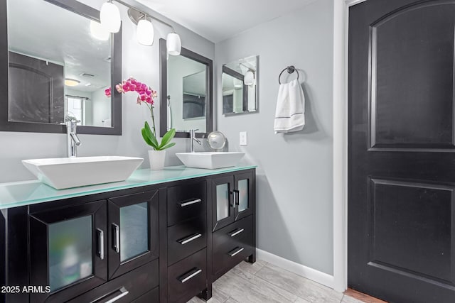 bathroom with double vanity, visible vents, baseboards, and a sink