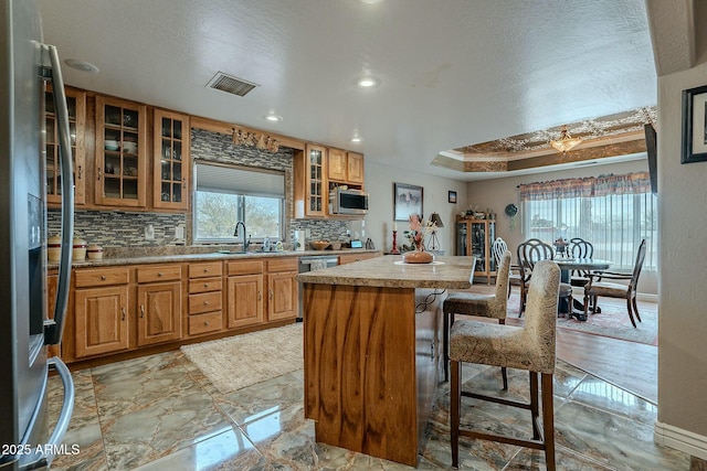 kitchen featuring sink, a breakfast bar area, appliances with stainless steel finishes, a kitchen island, and decorative backsplash