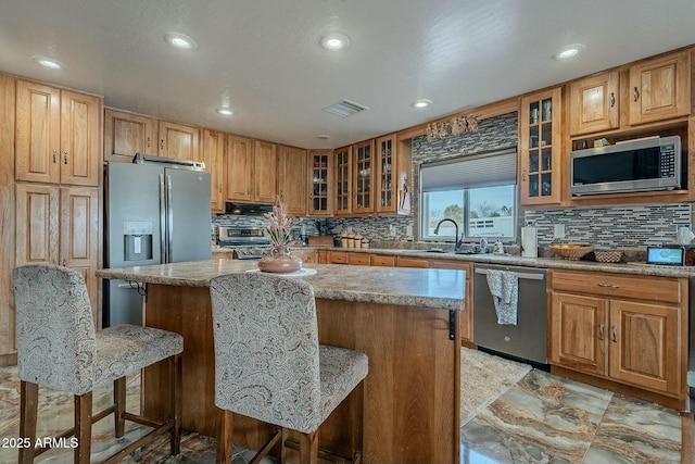 kitchen with stainless steel appliances, a breakfast bar, sink, and a kitchen island