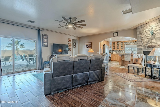 living room featuring sink, ornamental molding, and ceiling fan