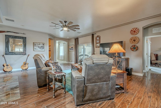 living room with hardwood / wood-style flooring, ceiling fan, and ornamental molding