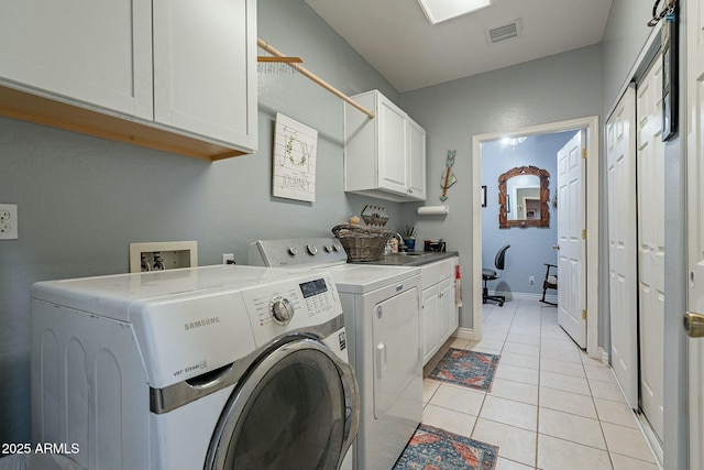 washroom with washer and clothes dryer, cabinets, and light tile patterned flooring