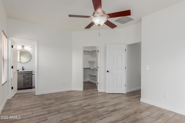2326 E Spruce Dr, Chandler, AZ 85286 - unfurnished bedroom featuring light wood-type flooring, a walk in closet, a sink, and baseboards