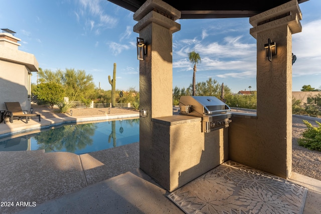 view of swimming pool with area for grilling, a patio area, and exterior kitchen