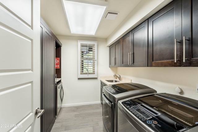 laundry room with cabinets, washer and clothes dryer, sink, and light wood-type flooring