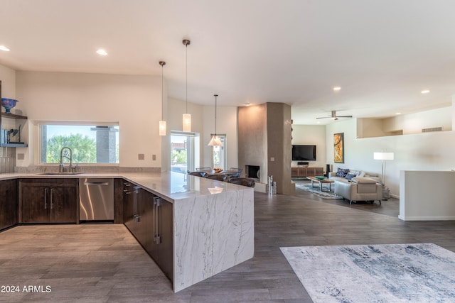 kitchen with sink, dark wood-type flooring, dishwasher, light stone countertops, and kitchen peninsula