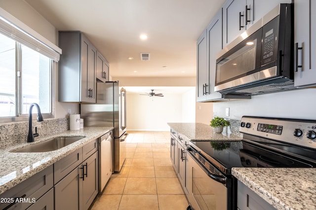 kitchen featuring visible vents, light tile patterned flooring, stainless steel appliances, a ceiling fan, and a sink