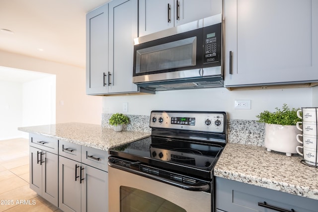 kitchen featuring light tile patterned floors, gray cabinets, appliances with stainless steel finishes, and light stone countertops