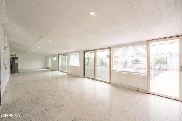 unfurnished room with recessed lighting, speckled floor, and electric water heater