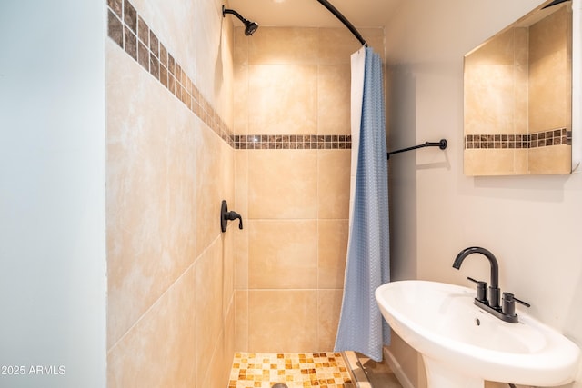 full bathroom featuring a tile shower and a sink