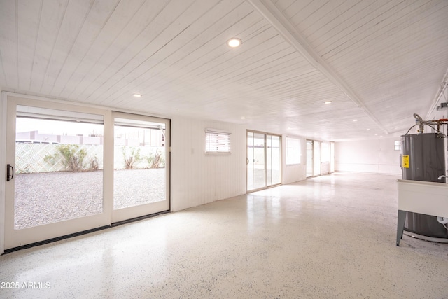 interior space featuring wood ceiling, speckled floor, a wealth of natural light, and electric water heater