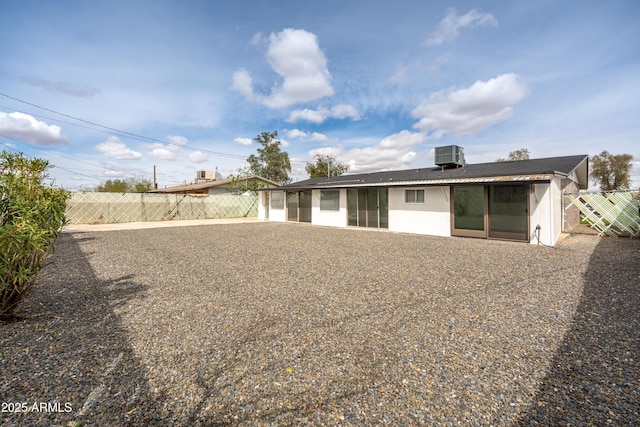 rear view of property featuring cooling unit, stucco siding, and fence