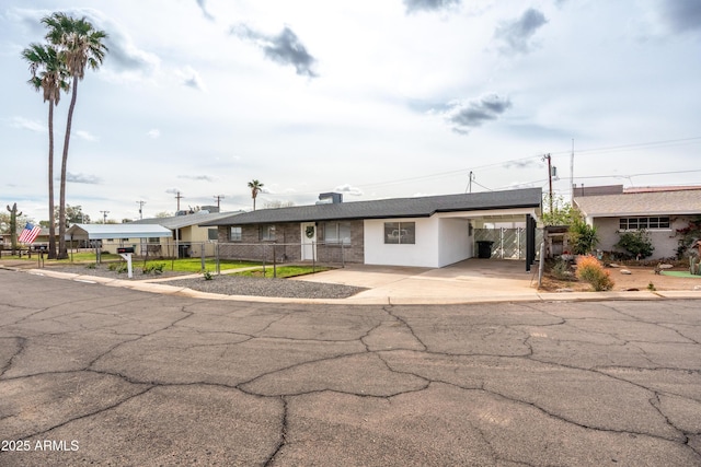 view of front of property featuring a carport, stucco siding, driveway, and fence