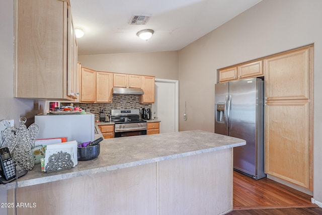 kitchen featuring decorative backsplash, light brown cabinets, lofted ceiling, and appliances with stainless steel finishes