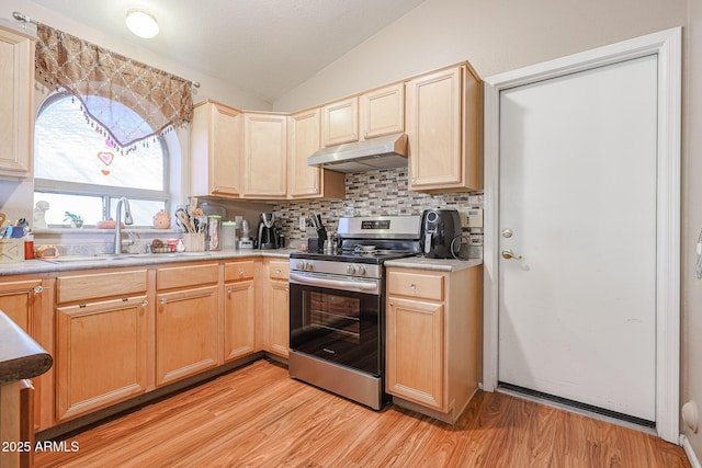 kitchen with backsplash, sink, vaulted ceiling, light wood-type flooring, and stainless steel range oven