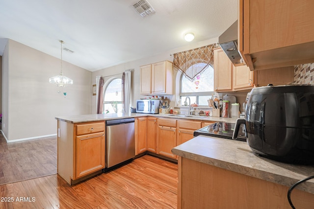 kitchen featuring kitchen peninsula, stainless steel appliances, sink, an inviting chandelier, and hanging light fixtures