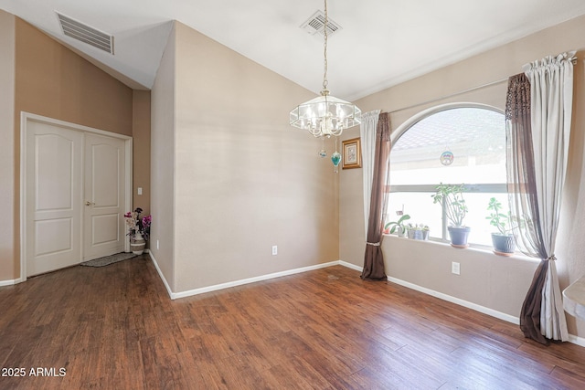 empty room featuring a notable chandelier, dark hardwood / wood-style floors, and lofted ceiling