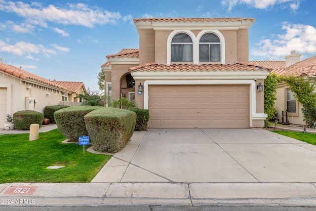 mediterranean / spanish-style house featuring a front yard and a garage