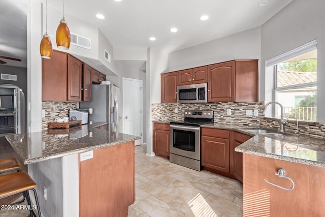 kitchen featuring pendant lighting, backsplash, dark stone counters, sink, and appliances with stainless steel finishes