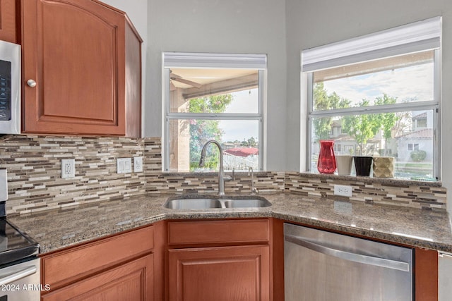 kitchen with tasteful backsplash, stainless steel dishwasher, sink, dark stone countertops, and range with electric stovetop