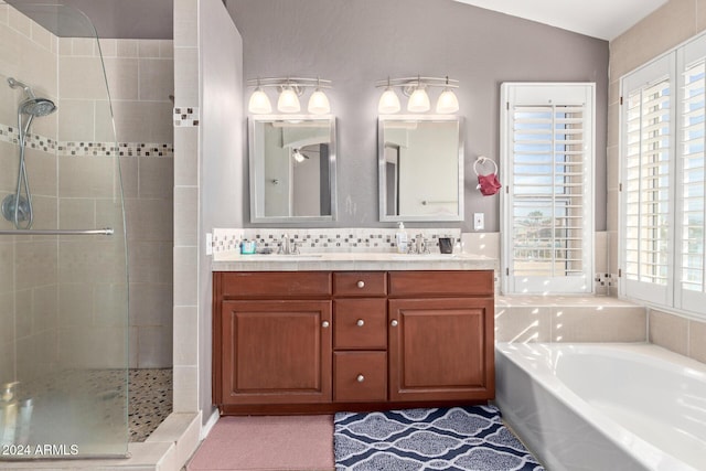 bathroom with vanity, lofted ceiling, backsplash, and independent shower and bath