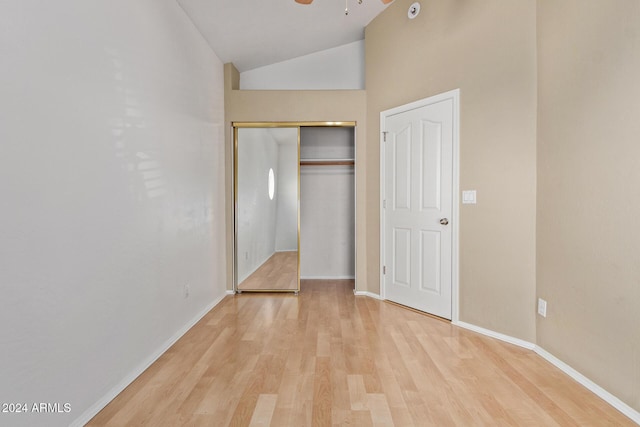 unfurnished bedroom featuring light hardwood / wood-style flooring, high vaulted ceiling, and a closet