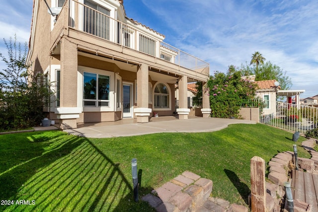 rear view of property featuring a lawn, a patio area, and a balcony