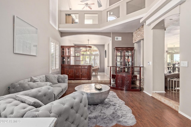 living room with hardwood / wood-style flooring, ceiling fan, and a towering ceiling